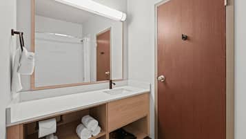 Un baño con un lavabo blanco, un espejo y una puerta de madera.