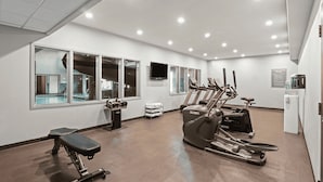 Un gimnasio con cintas de correr, una bicicleta estática y un banco.