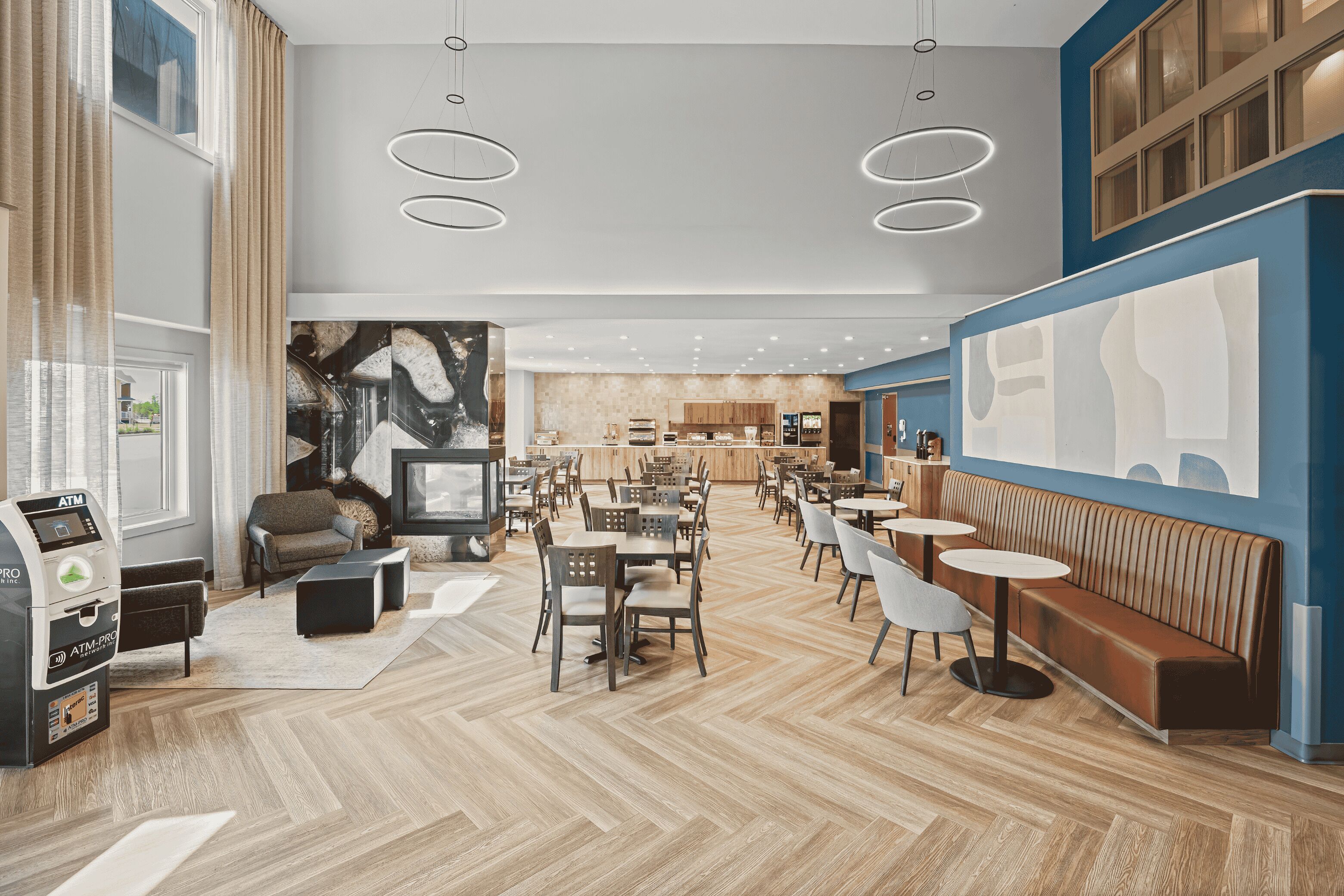 A spacious restaurant with a modern interior, featuring a mix of seating options including tables, chairs, and a long bench.