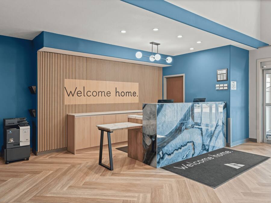 A reception area with a 'Welcome home' sign, a reception desk, a computer, and a printer.