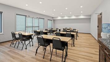 A conference room with multiple tables and chairs, large windows, and a water dispenser.