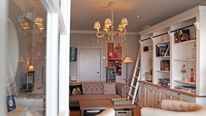 A living room with a sofa, armchairs, a coffee table, a bookshelf, and a chandelier. - Ara Dune Hotel (De Panne)