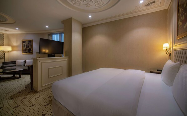 Habitación de hotel con una cama grande, televisión, sofá y escritorio.