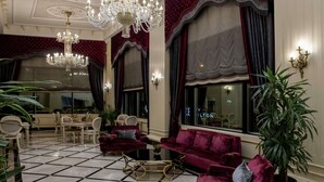 Un lobby lujoso con candelabro, asientos mullidos y piso a cuadros.