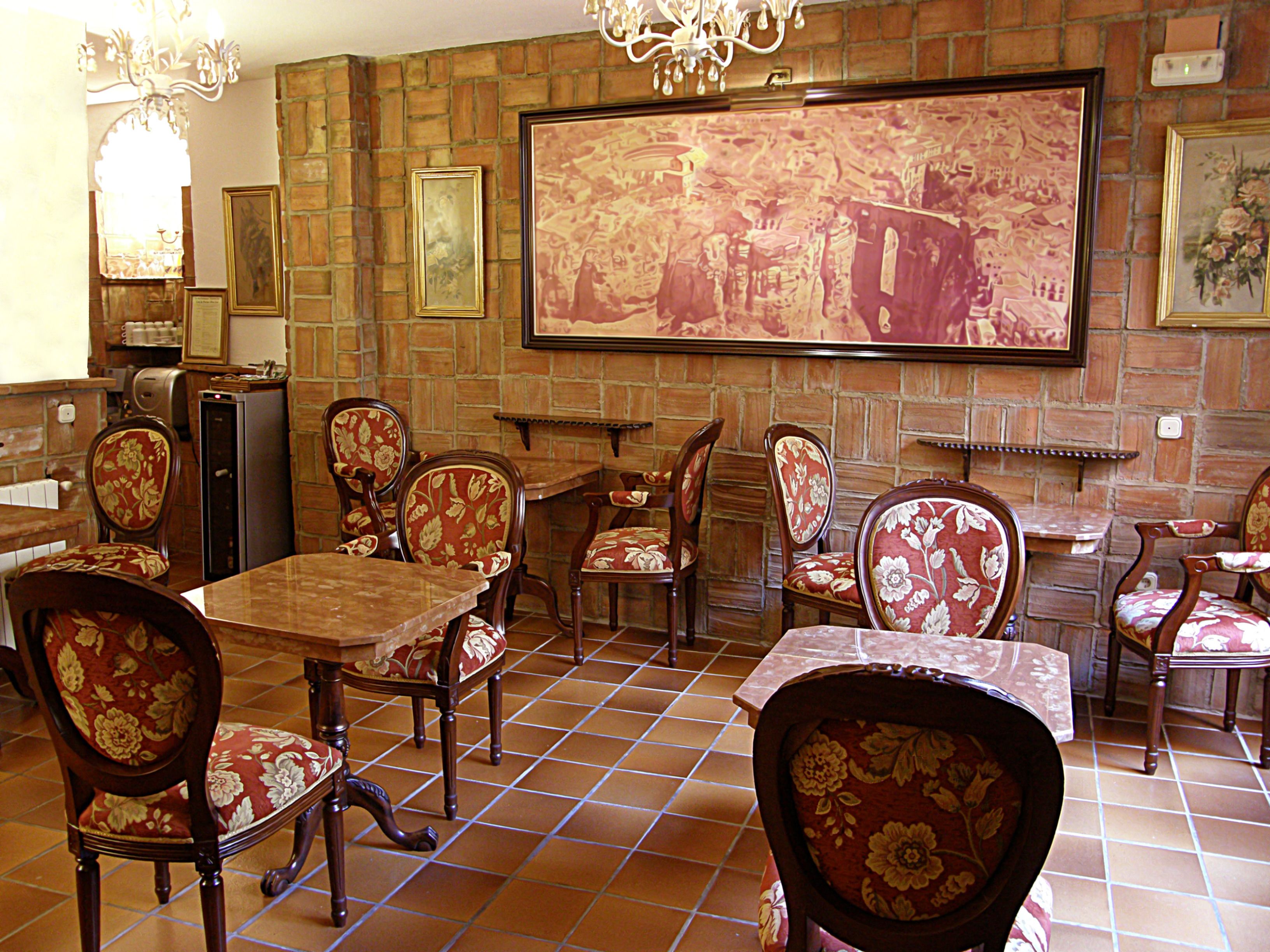 Un interior de restaurante con paredes de ladrillo, mesas de madera y sillas tapizadas con motivos florales.