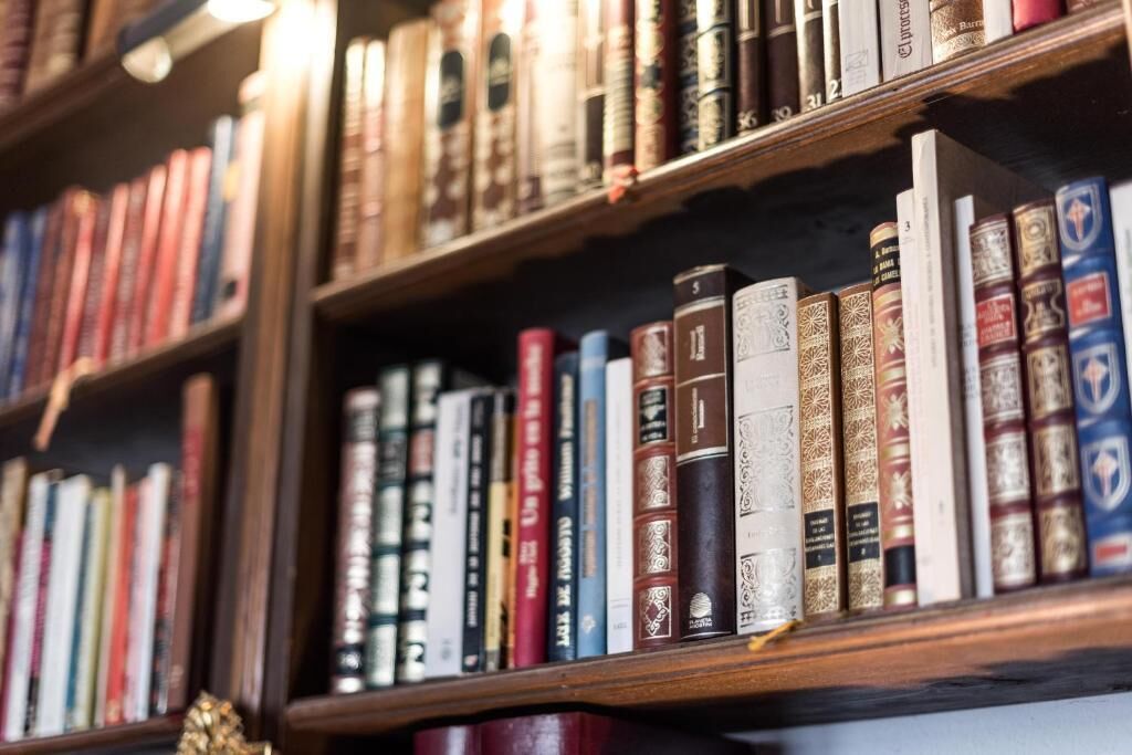 A bookshelf filled with various books, some with spines visible.