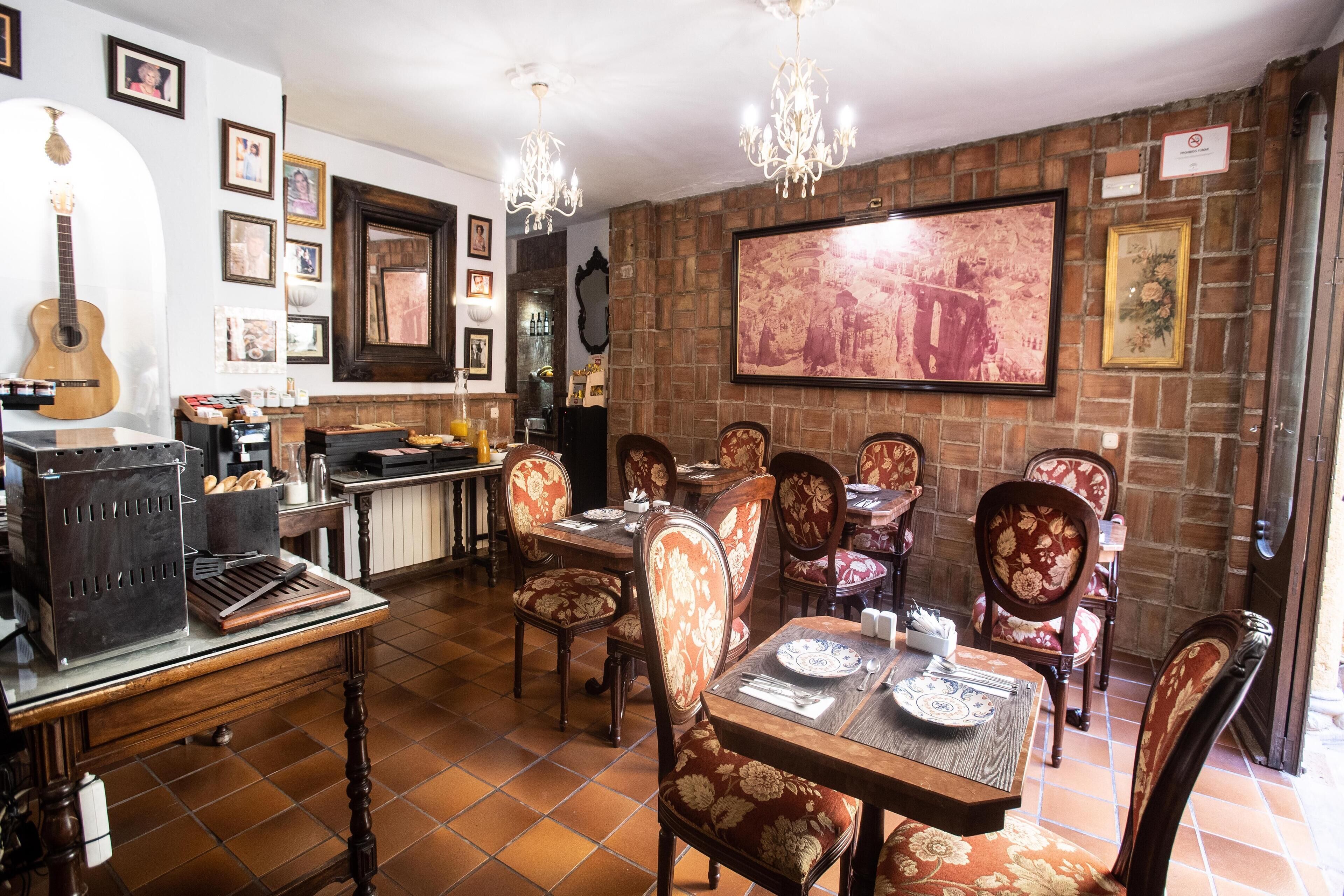 A dining area with a brick wall, wooden chairs, and a large painting.