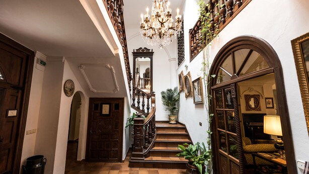Un vaste hall d’entrée avec un escalier, des portes en bois et un lustre.