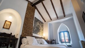 Une chambre à coucher avec un lit, un bureau, une chaise, une fenêtre donnant sur un beau paysage et un mur en briques.