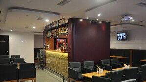 A restaurant with a bar area, seating, and a television screen. - Hotel Pandian (Chennai)