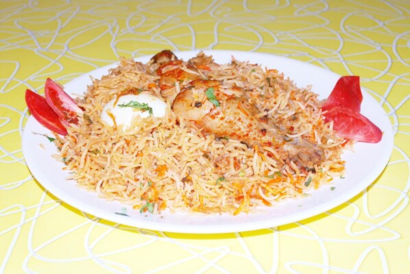 A plate of biryani with a boiled egg and garnished with red bell peppers. - Hotel Pandian (Chennai)