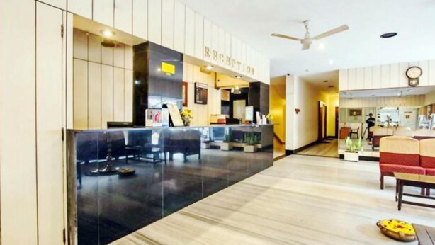 A hotel lobby with a reception desk, seating area, and a ceiling fan. - Hotel Pandian (Chennai)
