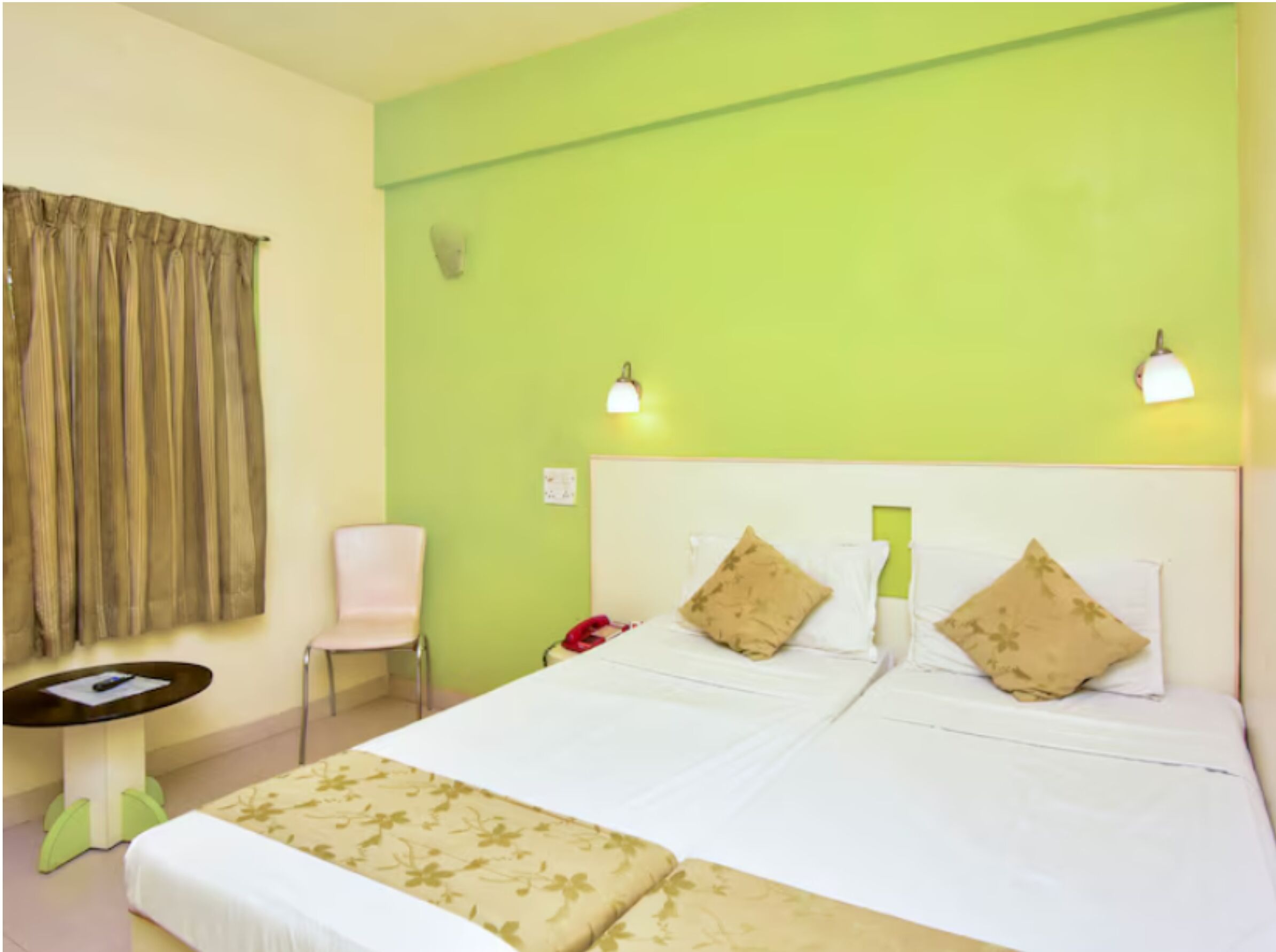 A hotel room with a large bed, two bedside lamps, a chair, and a small table.
