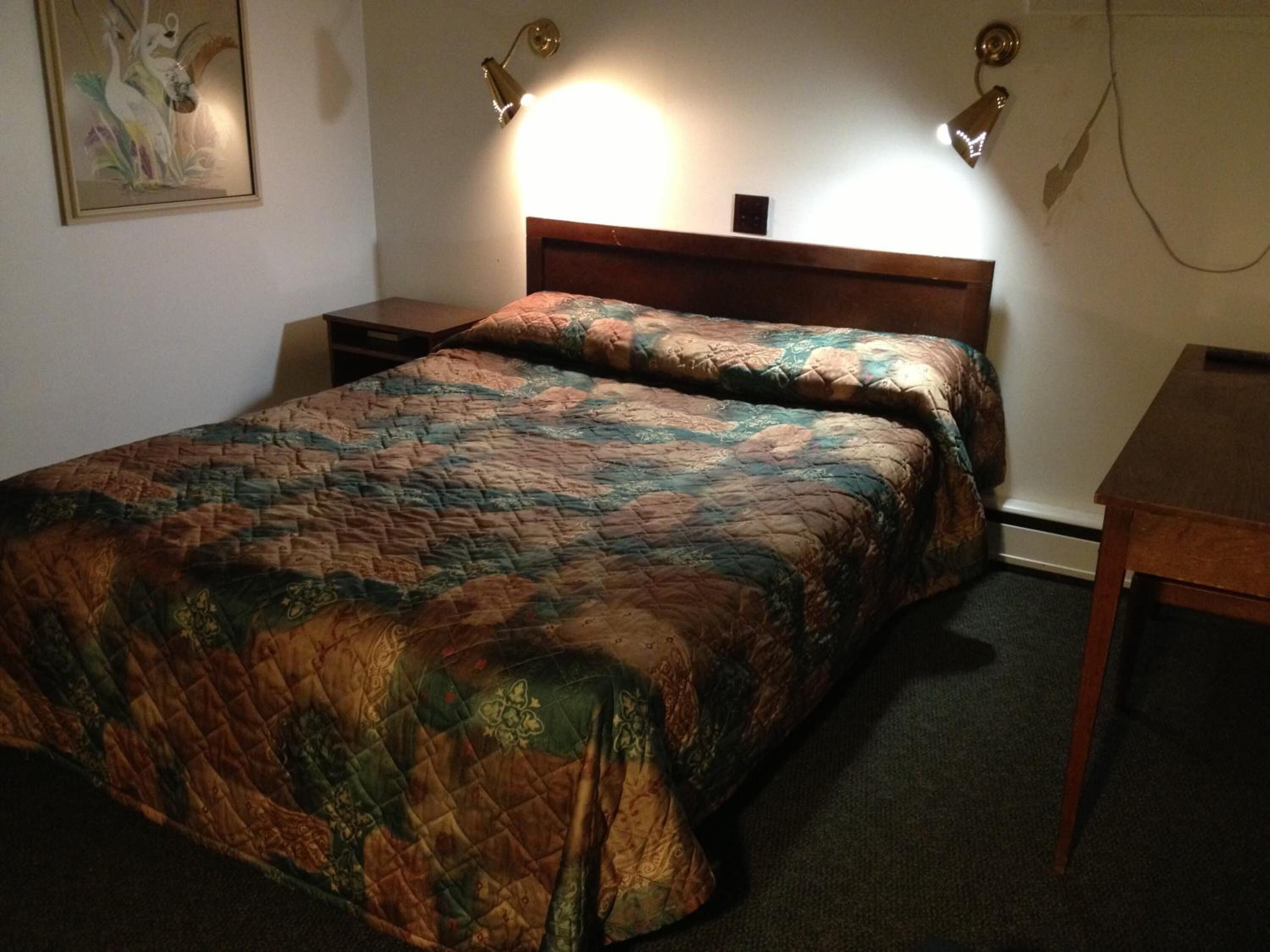 A standard hotel room with a bed, bedside tables, and a small desk.