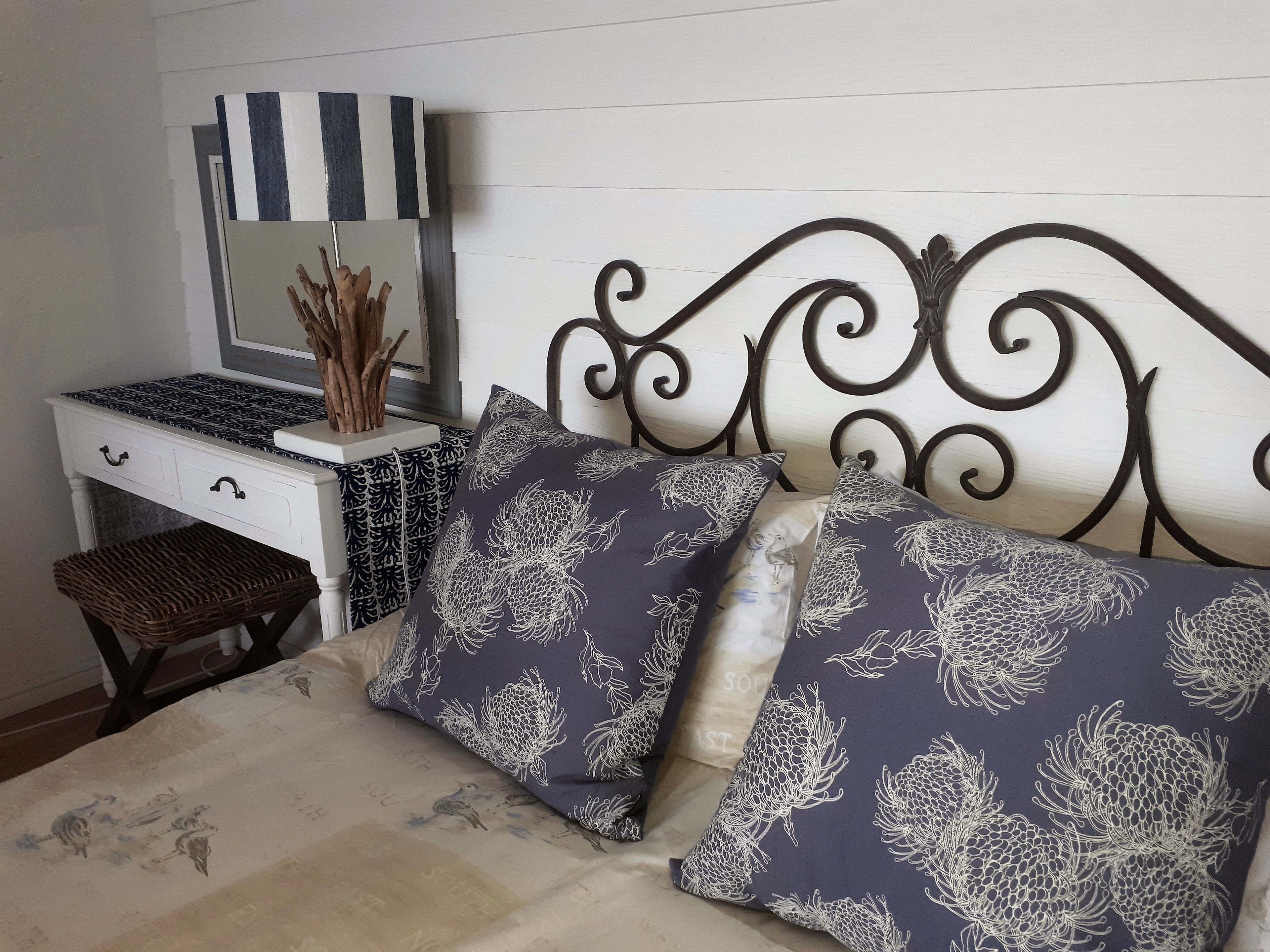 Un dormitorio con cama, cómoda, espejo y un pequeño banco.