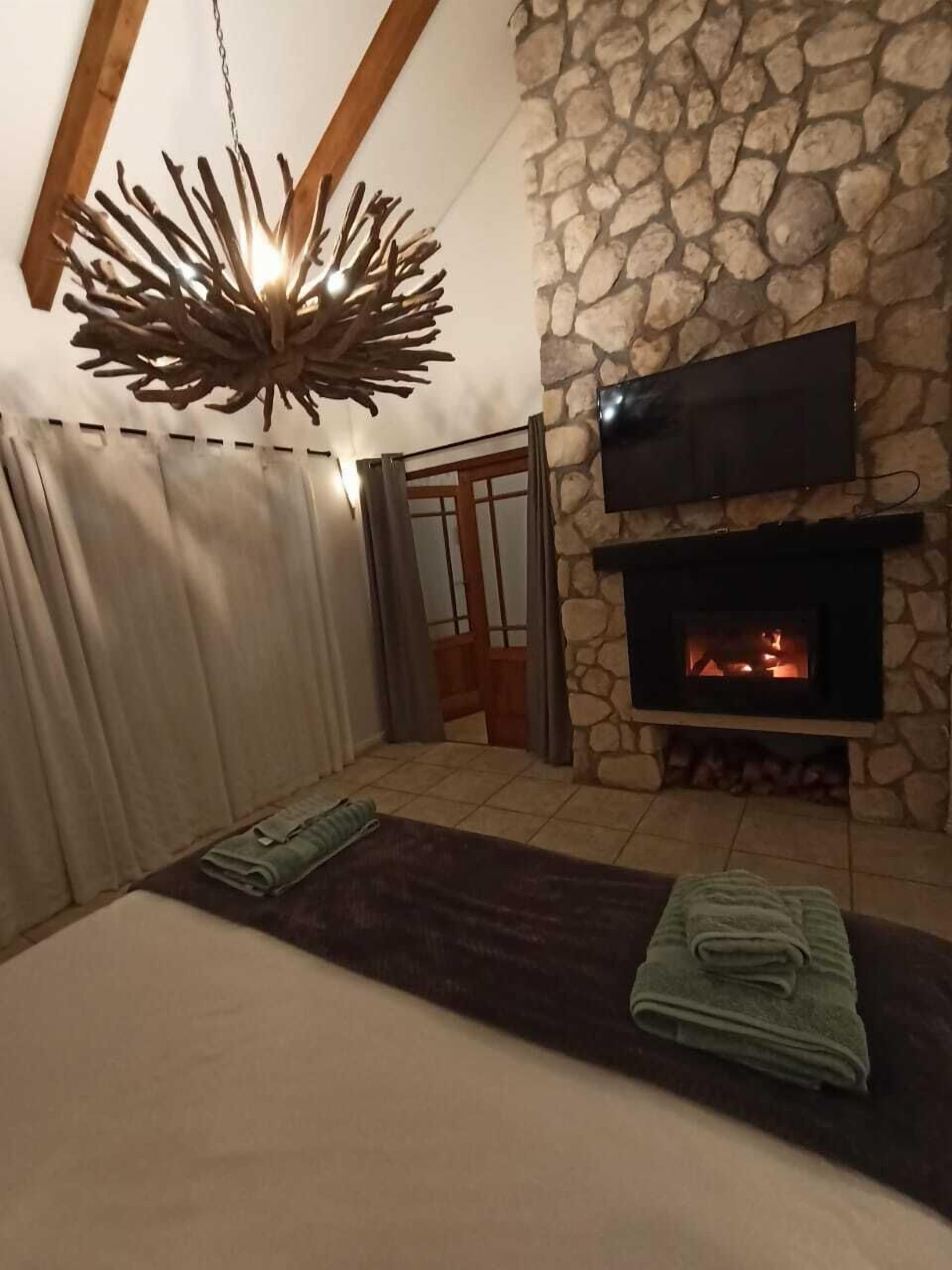 Una habitación acogedora con chimenea de piedra, televisor de pantalla plana y una lámpara de madera original.