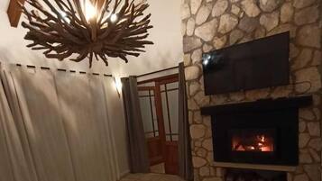 Una habitación acogedora con chimenea de piedra, televisor de pantalla plana y una lámpara de madera original.