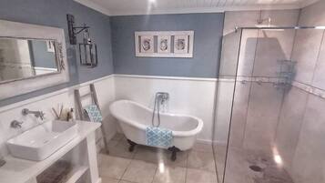 A bathroom with a freestanding bathtub, a sink, and a glass-enclosed shower.