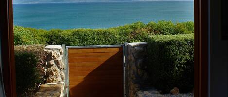A view of a coastal landscape through a wooden door, with a wooden board game on a table in the foreground.
