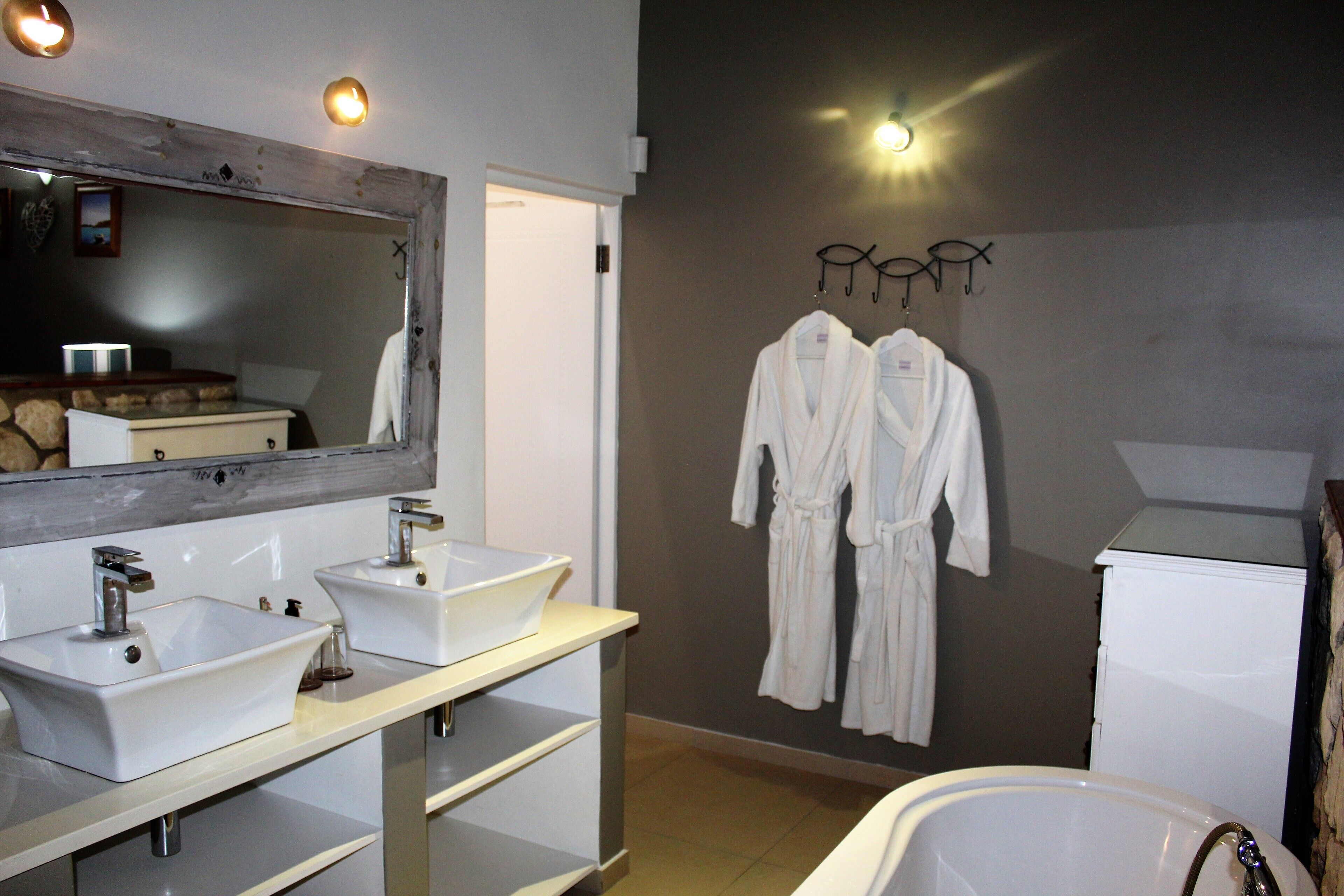 Un baño moderno con dos lavamanos, un espejo grande y una bañera.
