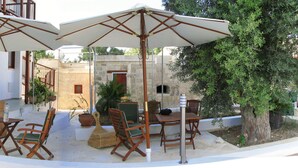 An outdoor seating area with a table and chairs, two umbrellas, and a potted plant. - Lasa Heights (Lasa)