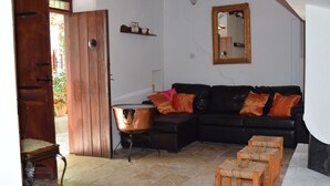 A living room with a black leather sofa, wooden stools, a copper pot, and a wooden table. - Lasa Heights (Lasa)