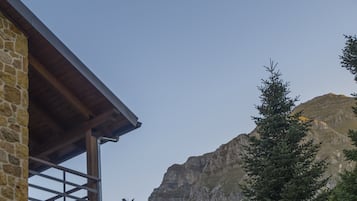 Ein Steingebäude mit einem hölzernen Balkon mit Blick auf eine Berglandschaft.