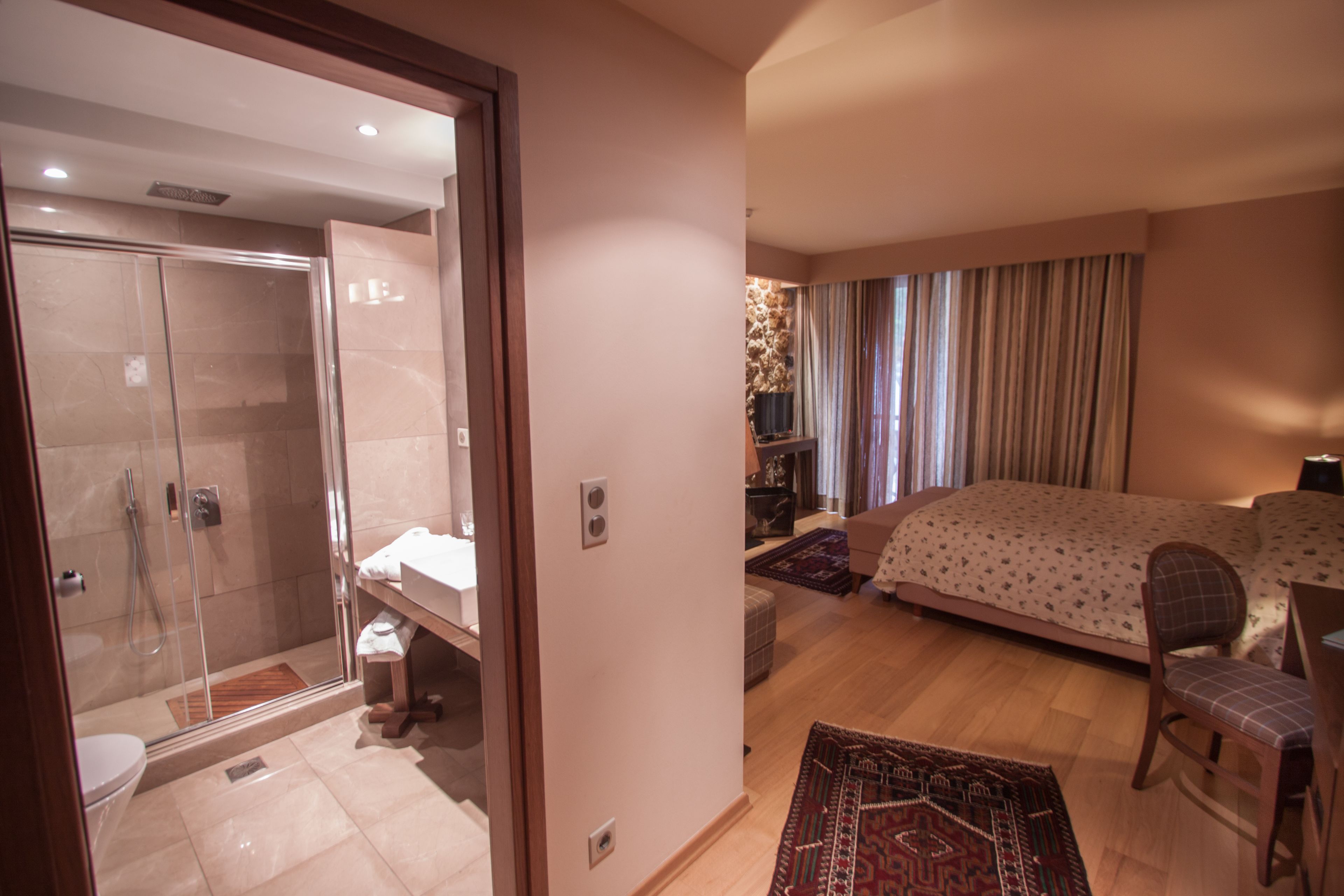 Una habitación de hotel con ducha, cama, silla y una pequeña mesa.