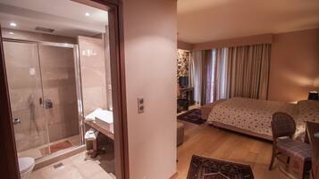 Una habitación de hotel con ducha, cama, silla y una pequeña mesa.