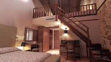 A bedroom with a bed, a desk, a chair, a staircase, and a small balcony.