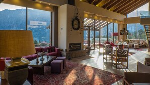 Un vaste espace de vie agrémenté d’une cheminée, de grandes fenêtres offrant une vue sur les montagnes et d’un coin salon confortable.
