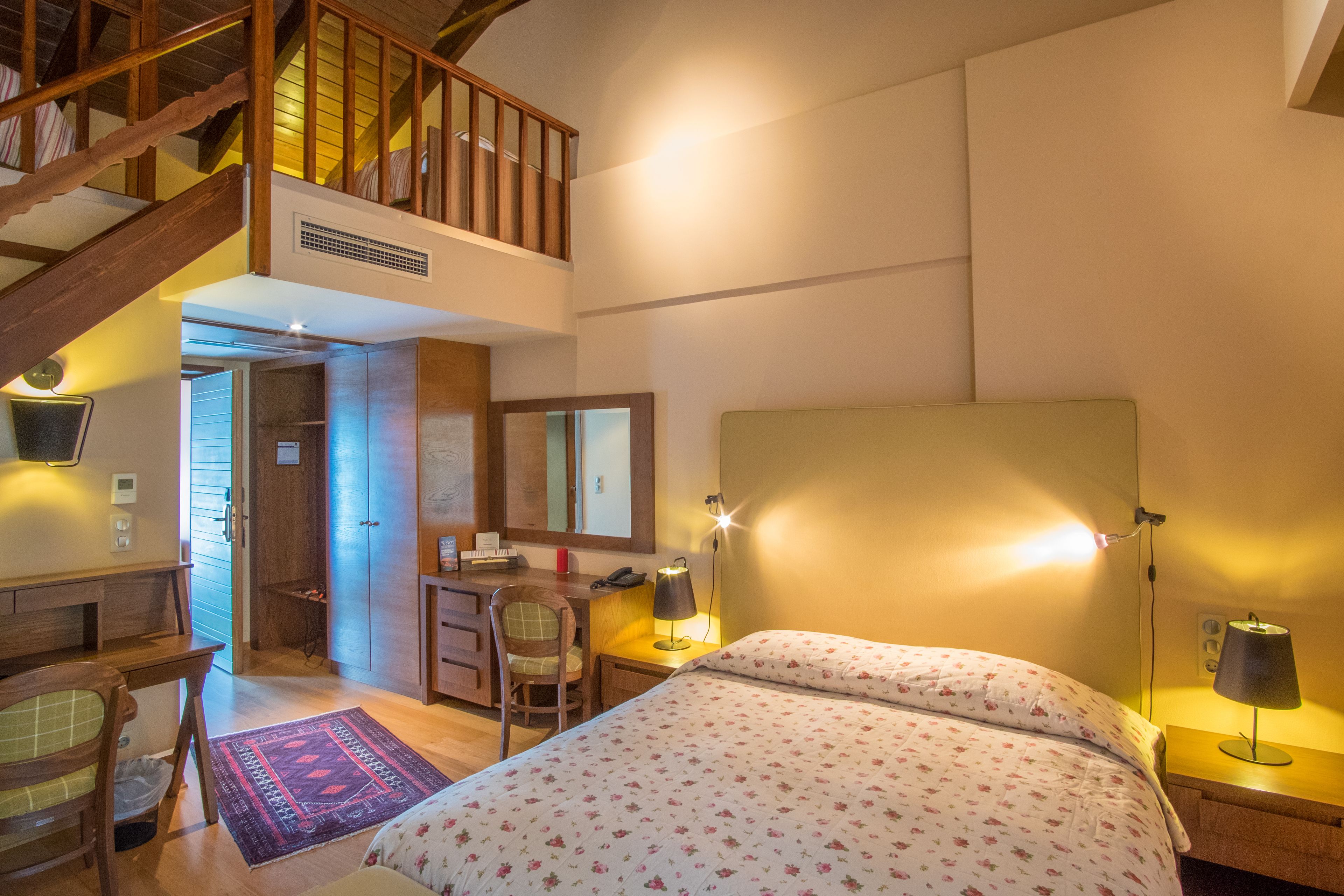 Un dormitorio con cama, escritorio, silla y una escalera.