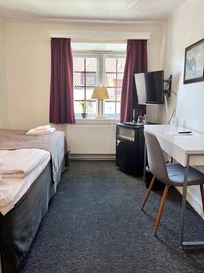 A hotel room with two beds, a desk with a chair, a TV, and a window with curtains. - Värdshuset Hwitan (Falkenberg)