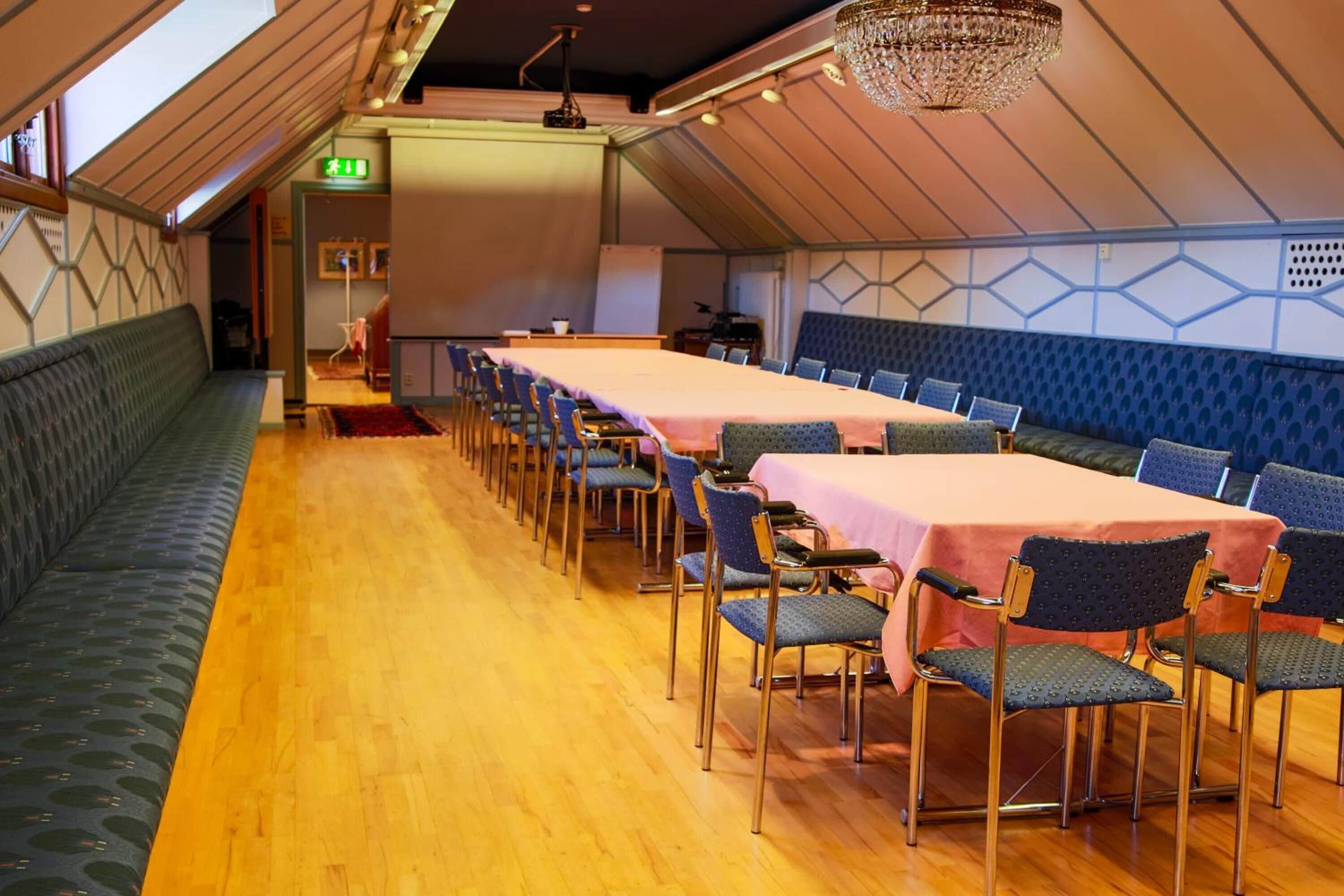 Een vergaderzaal met een lange tafel, stoelen en een groene bank.