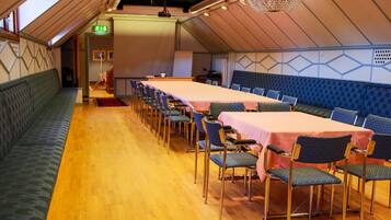 Een vergaderzaal met een lange tafel, stoelen en een groene bank.
