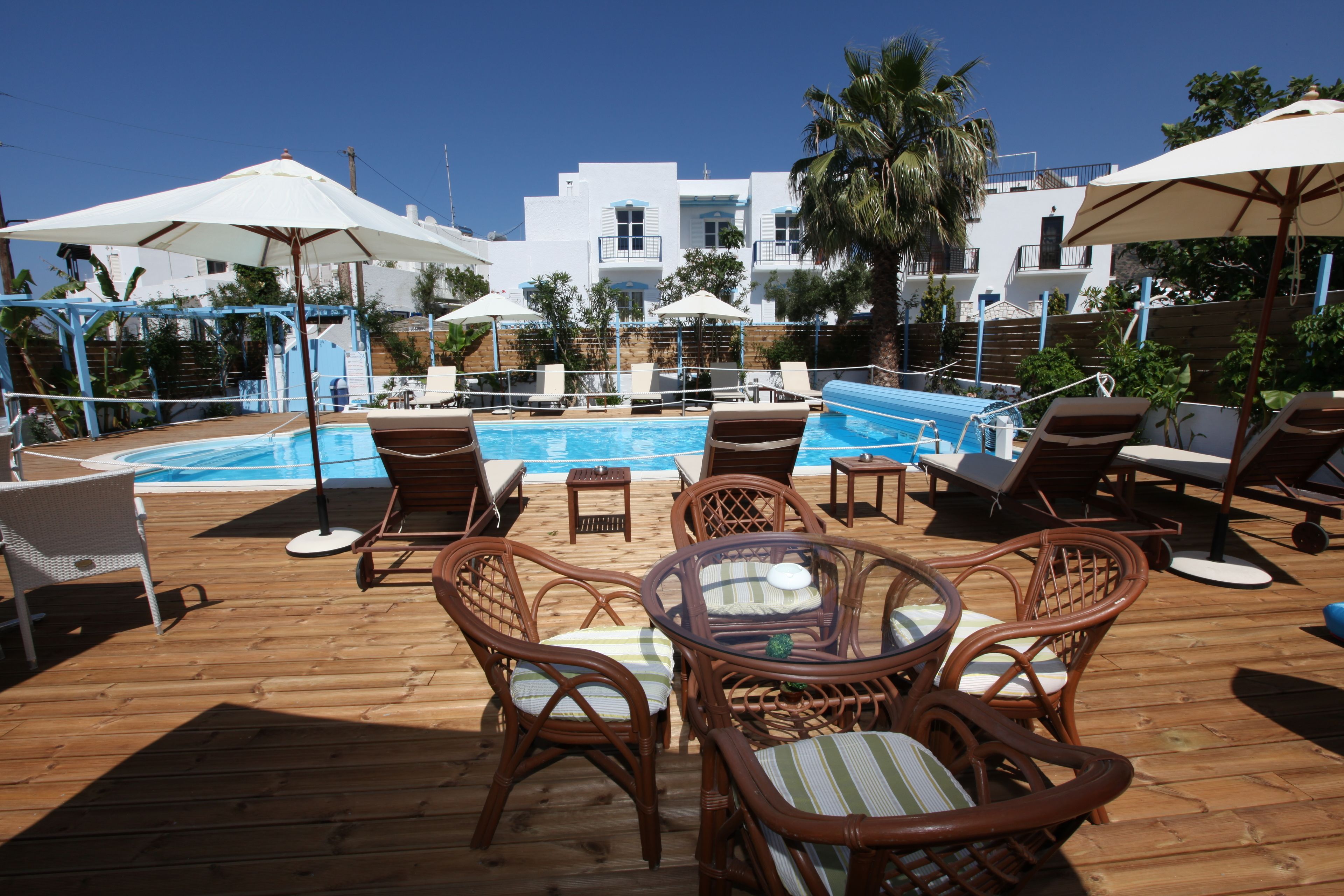 A poolside area with wicker chairs, a table, and umbrellas.