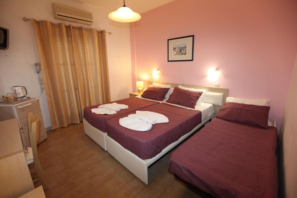 Habitación de hotel con dos camas, un escritorio, una silla y cortina de ducha.