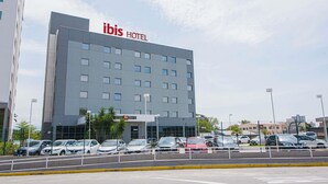 Een modern hotelgebouw met een opvallend “ibis HOTEL” bord.