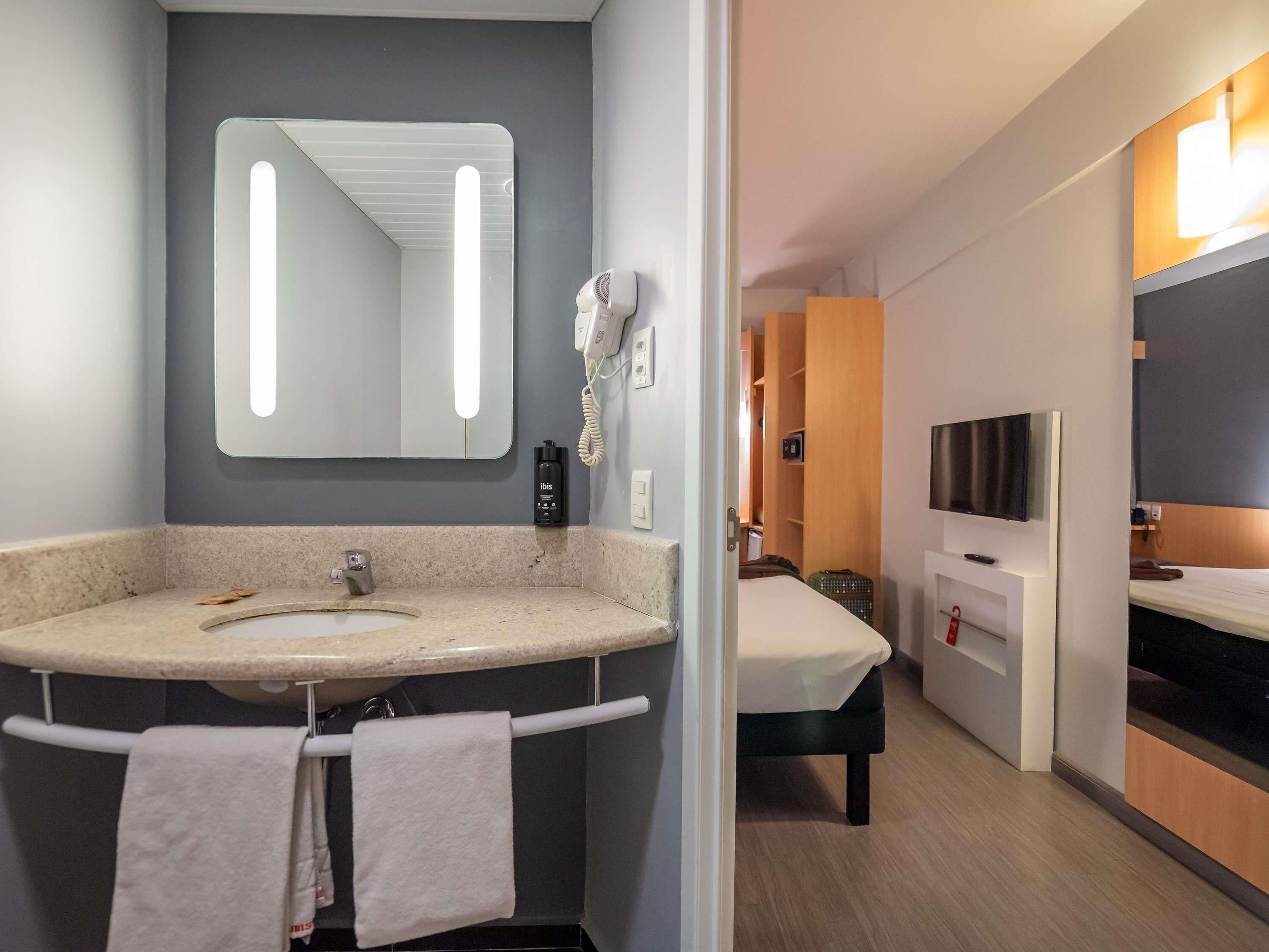 Ein modernes Badezimmer mit Waschbecken, Spiegel und Handtuchhalter.
