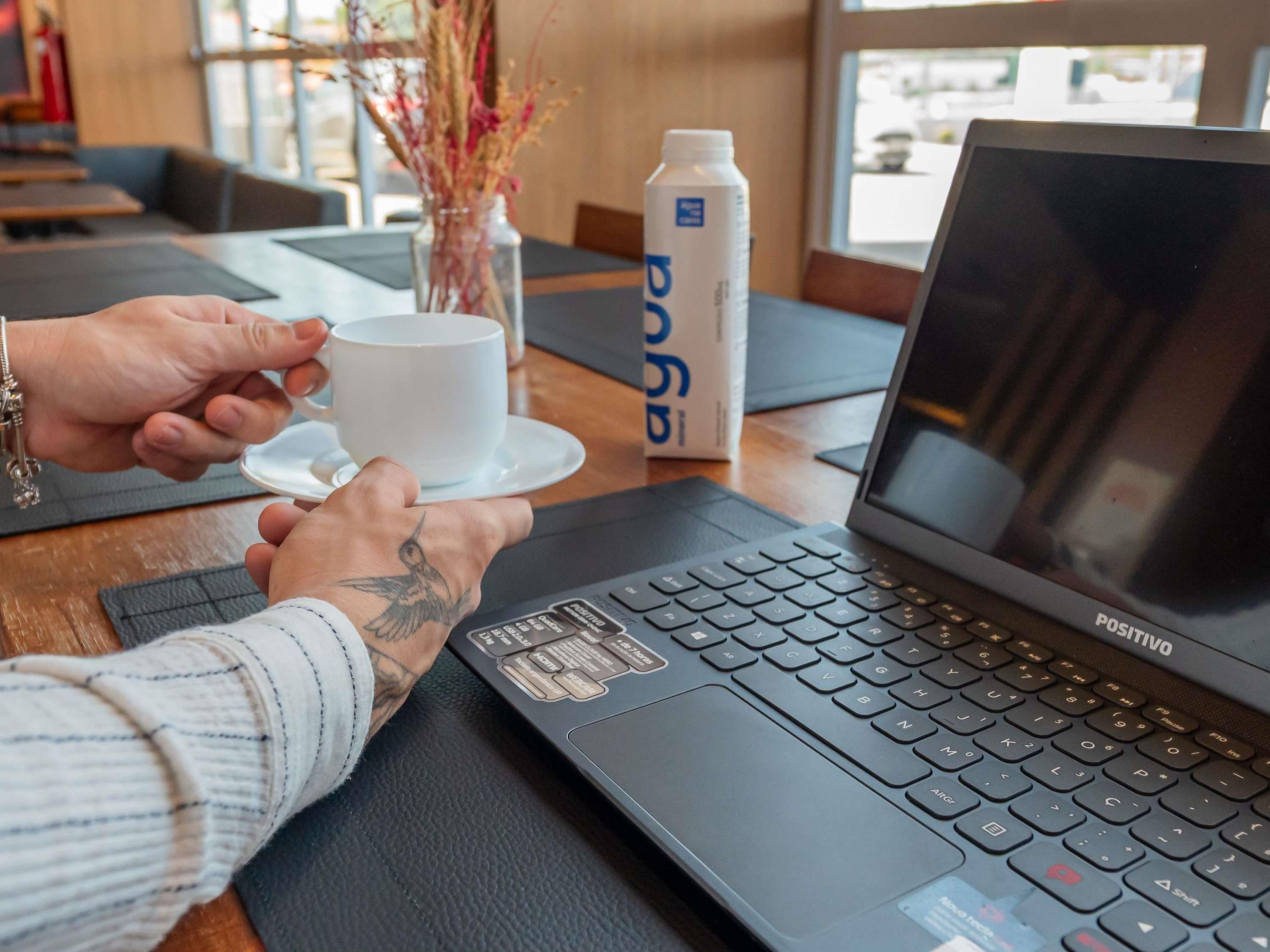 A laptop on a table with a cup and a bottle of water.