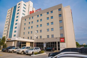 Un hotel de varios pisos, un estacionamiento con varios coches y un cielo despejado.