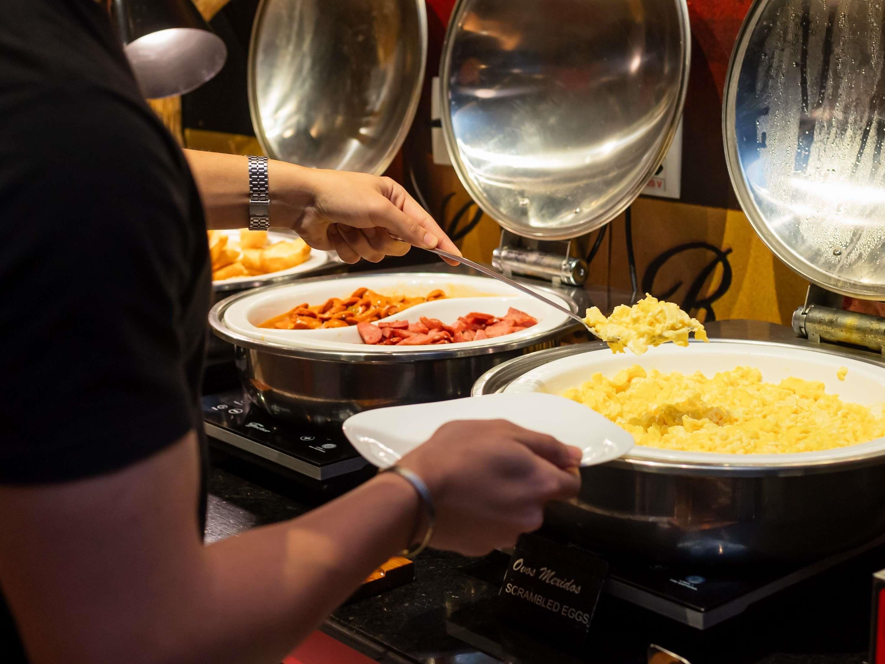 Un bufé con huevos revueltos, pasta y salchichas.