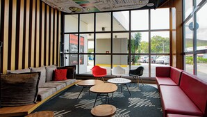 Een modern interieur met een bank, rode en witte stoelen en een salontafel.