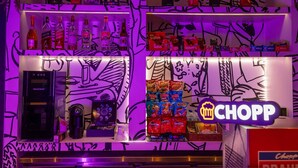 A bar area with shelves stocked with various bottles and snacks, a coffee machine, and a 'Chopp' sign. - Ibis Guaratinguetá Aparecida (Guaratingueta)