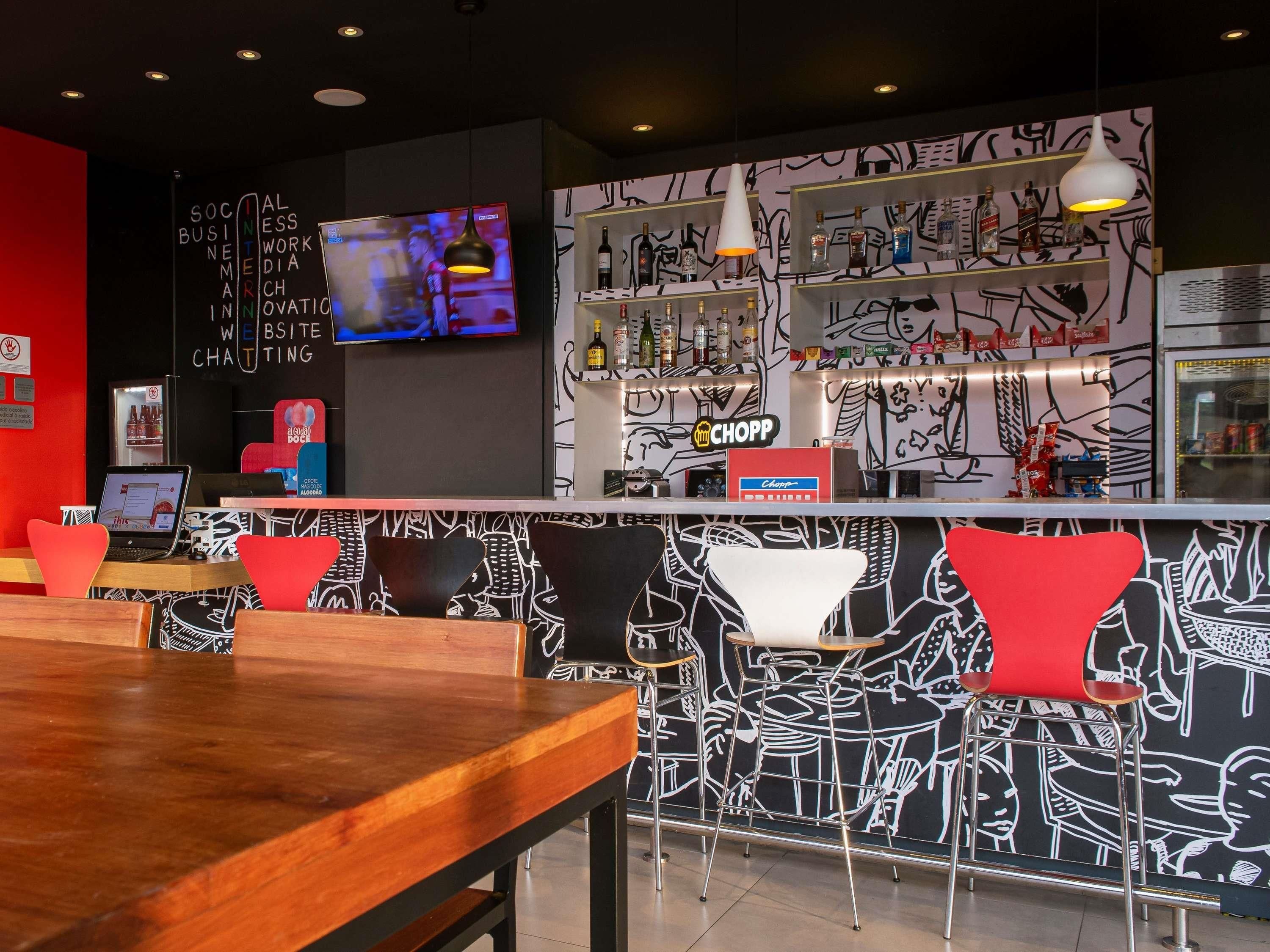 Zona de bar moderna con una pared de grafitis en blanco y negro, una pantalla de televisión y una variedad de botellas de licor.