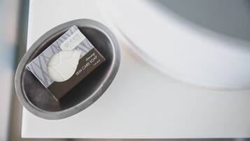 A bar of green Natura skin care soap on a white surface.