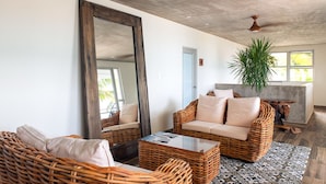 Un espacio habitable amplio con muebles de mimbre, un espejo grande y un ventilador de techo.