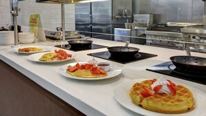Ein Frühstücksbuffet mit verschiedenen Speisen, darunter Waffeln, Omeletts und Pfannkuchen.