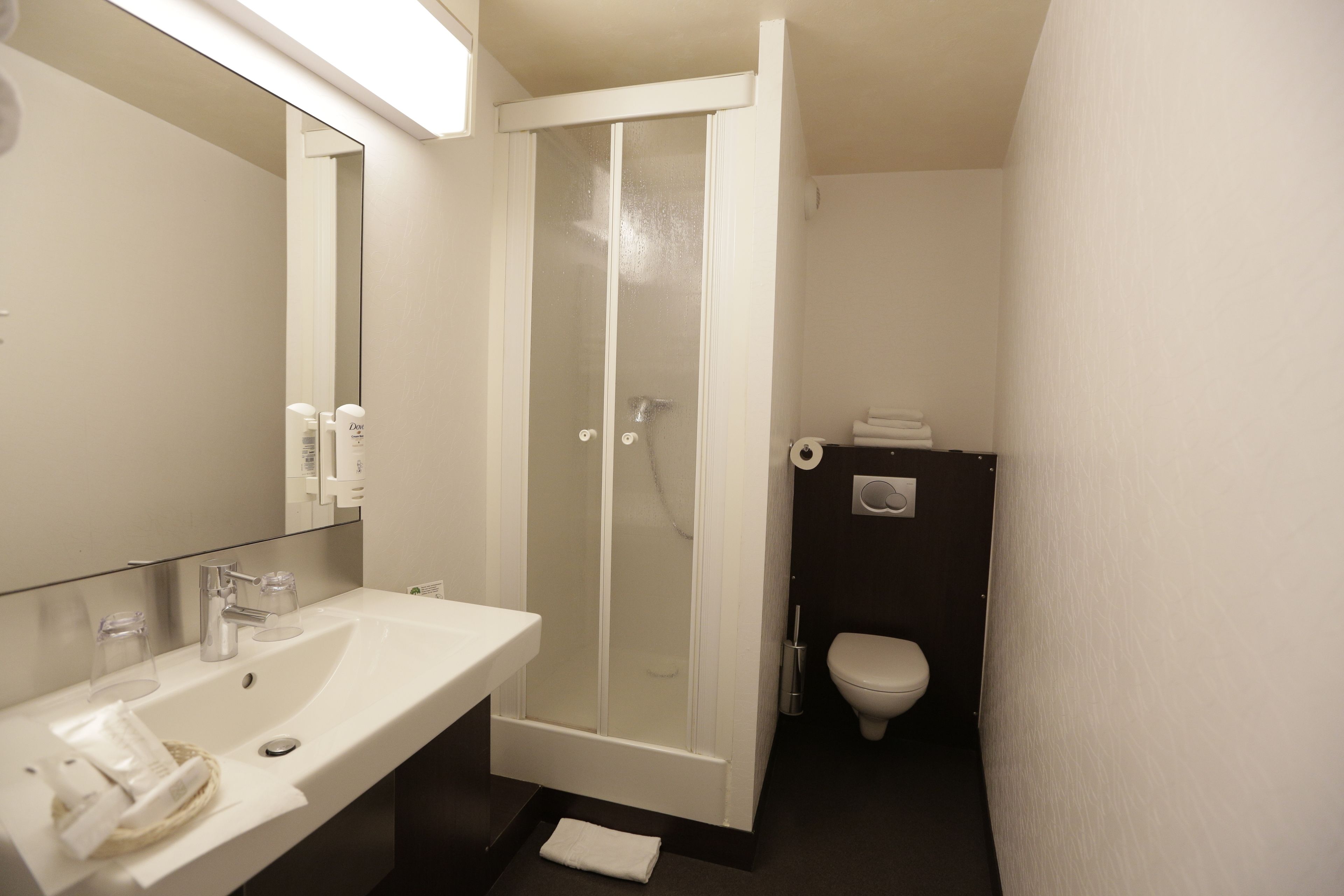 A bathroom with a white sink, a glass-enclosed shower, and a toilet.