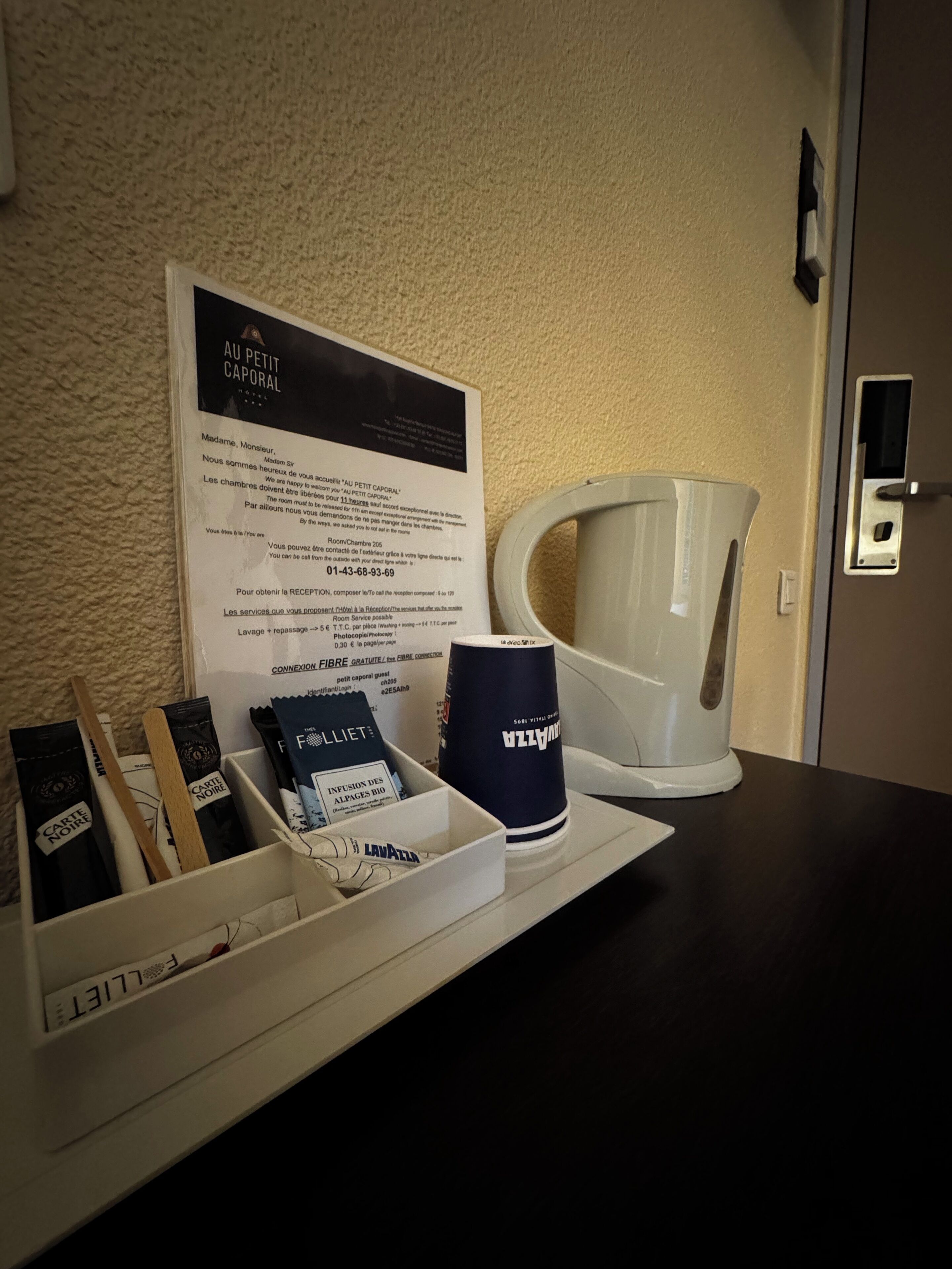 A hotel reception area with a signboard, a coffee machine, and a tray with toiletries.
